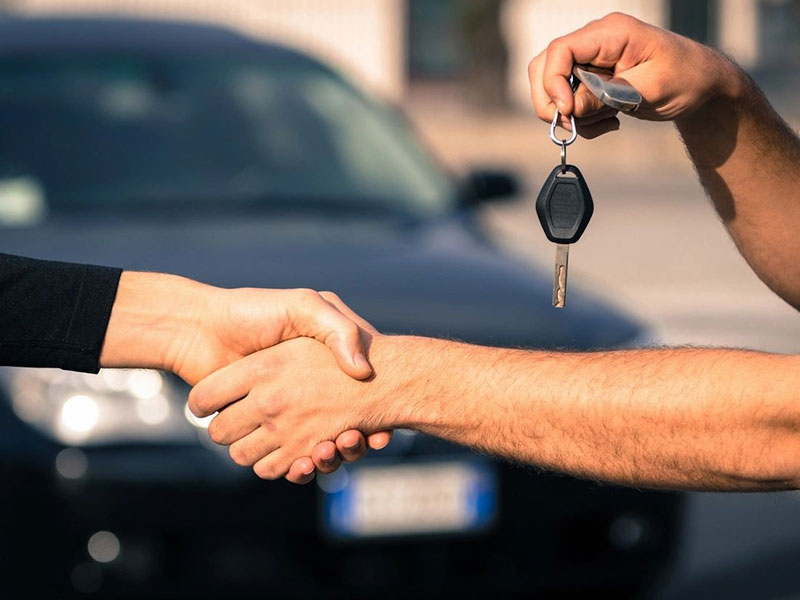 A man shaking hands with another person holding keys.